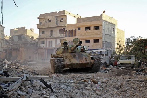 A member of the self-styled Libyan National Army, loyal to the country's east strongman Khalifa Haftar, rides in a tank as it drives down a street through the rubble in Benghazi's central Akhribish district on July 19, 2017 following clashes with militants. Libyan military strongman Khalifa Haftar on July 5, 2017 announced the "total liberation" of second city Benghazi, which was overrun by jihadists three years prior. / AFP PHOTO / Abdullah DOMA